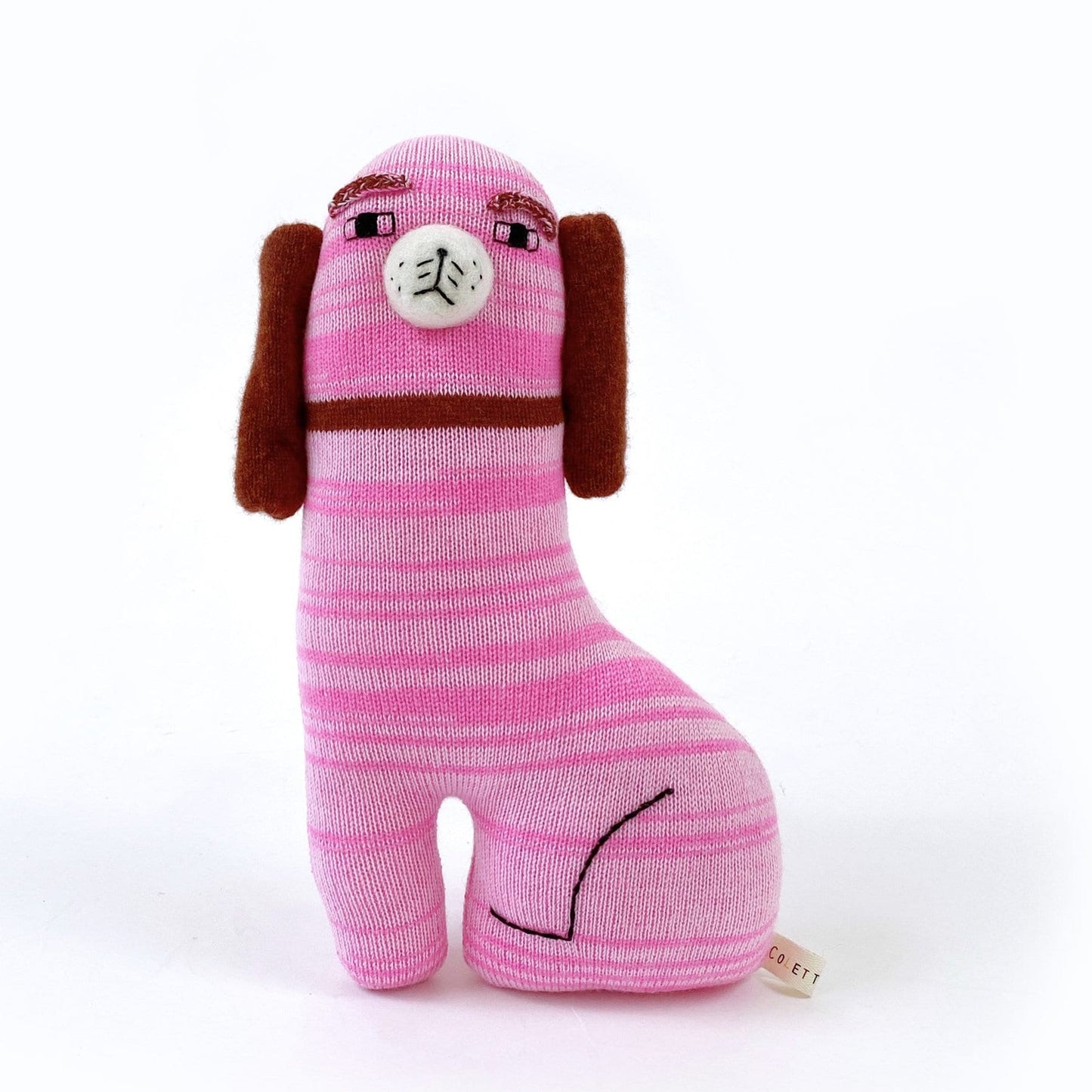 Pink knitted Staffordshire dog-shaped toy with brown ears on a white background