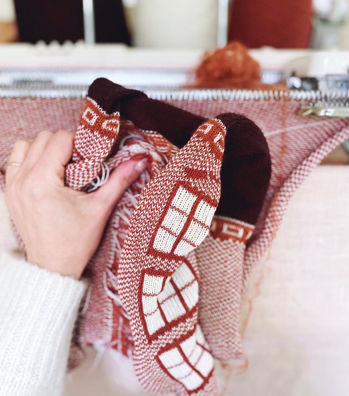 Hand holding a knitted item with a pattern, blurred background