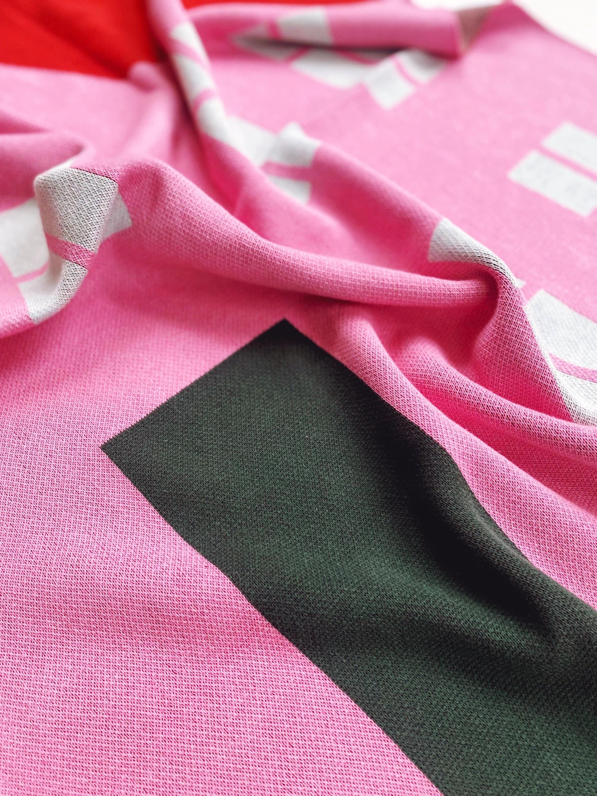 Close-up of a pink knitted fabric with a house design