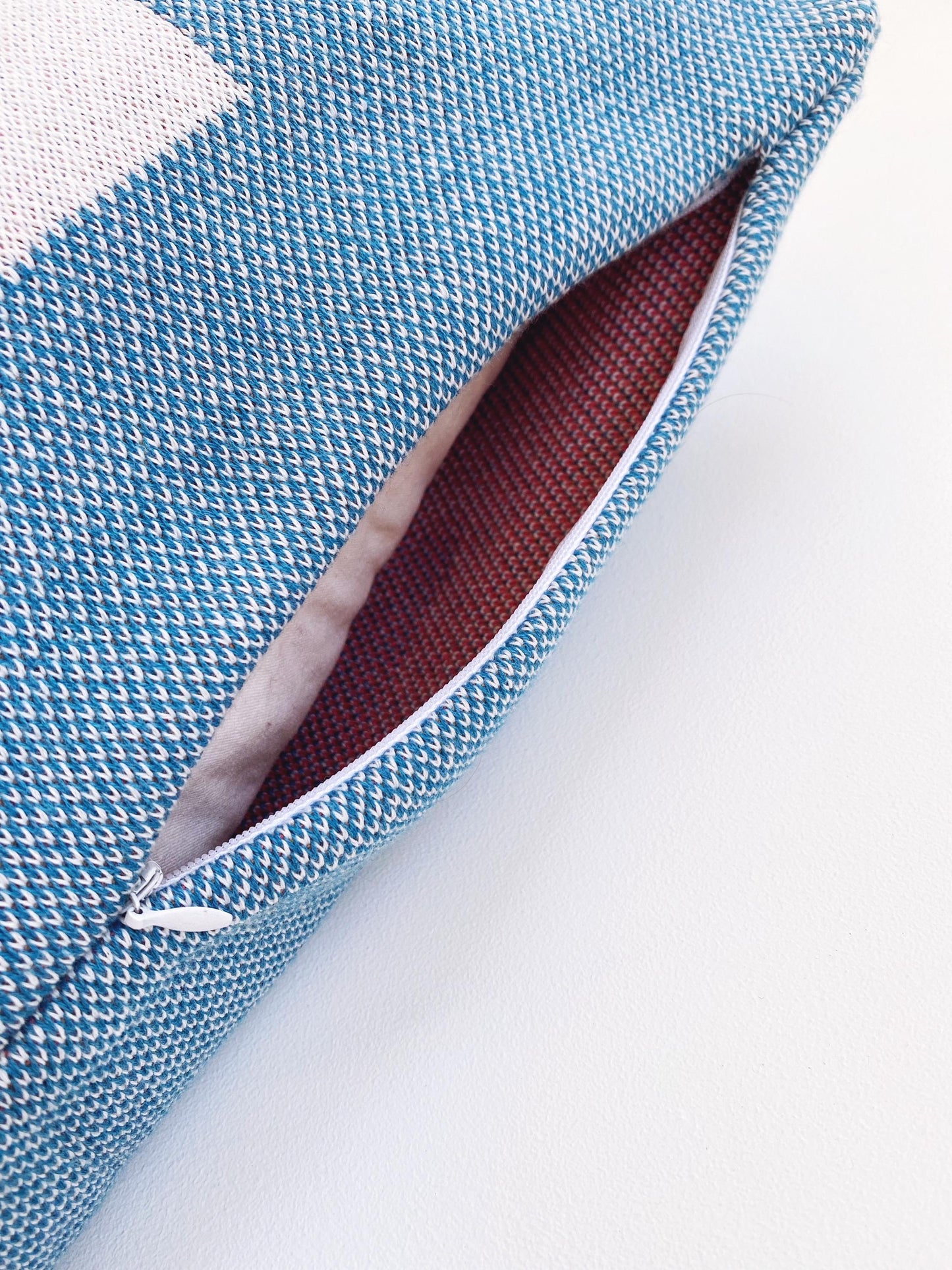 Blue textured knitted fabric pillow with zipper closure on a white background