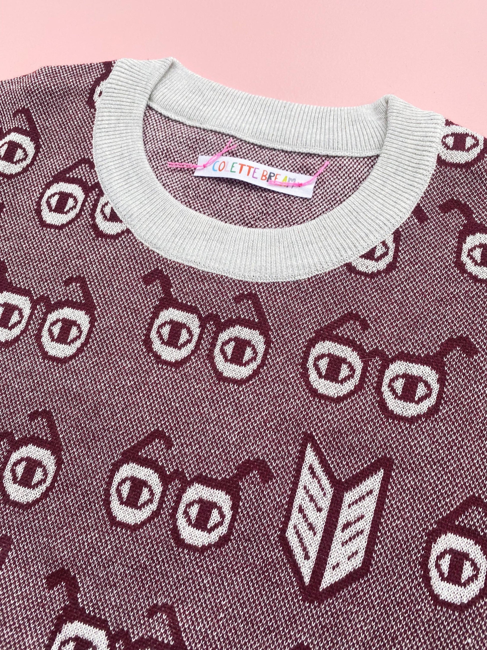 Knitted sweater with eyeglasses themed pattern on a pink background