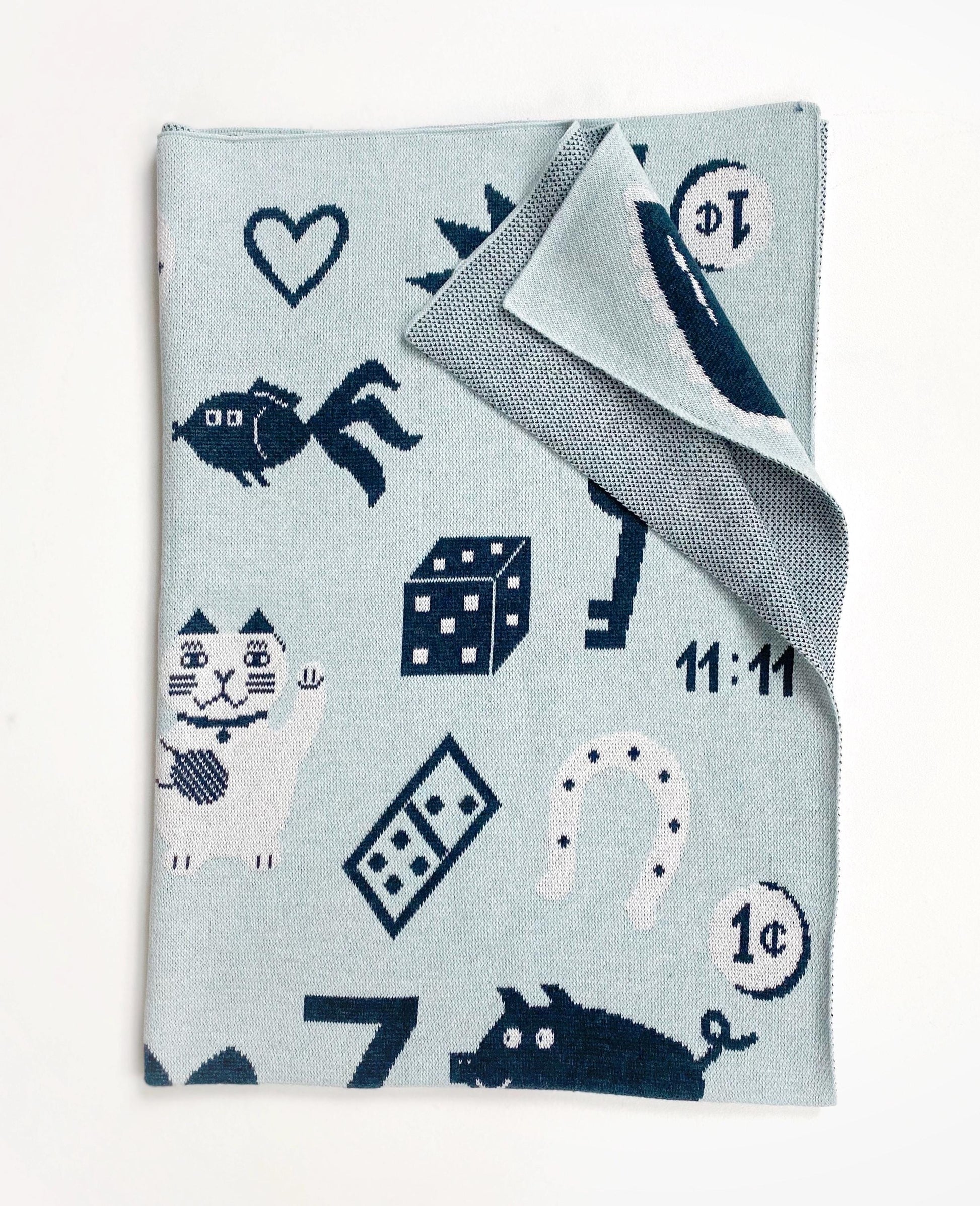Knit baby blanket with blue and gray pattern featuring numbers, animals, and good luck symbols on a light blue background.