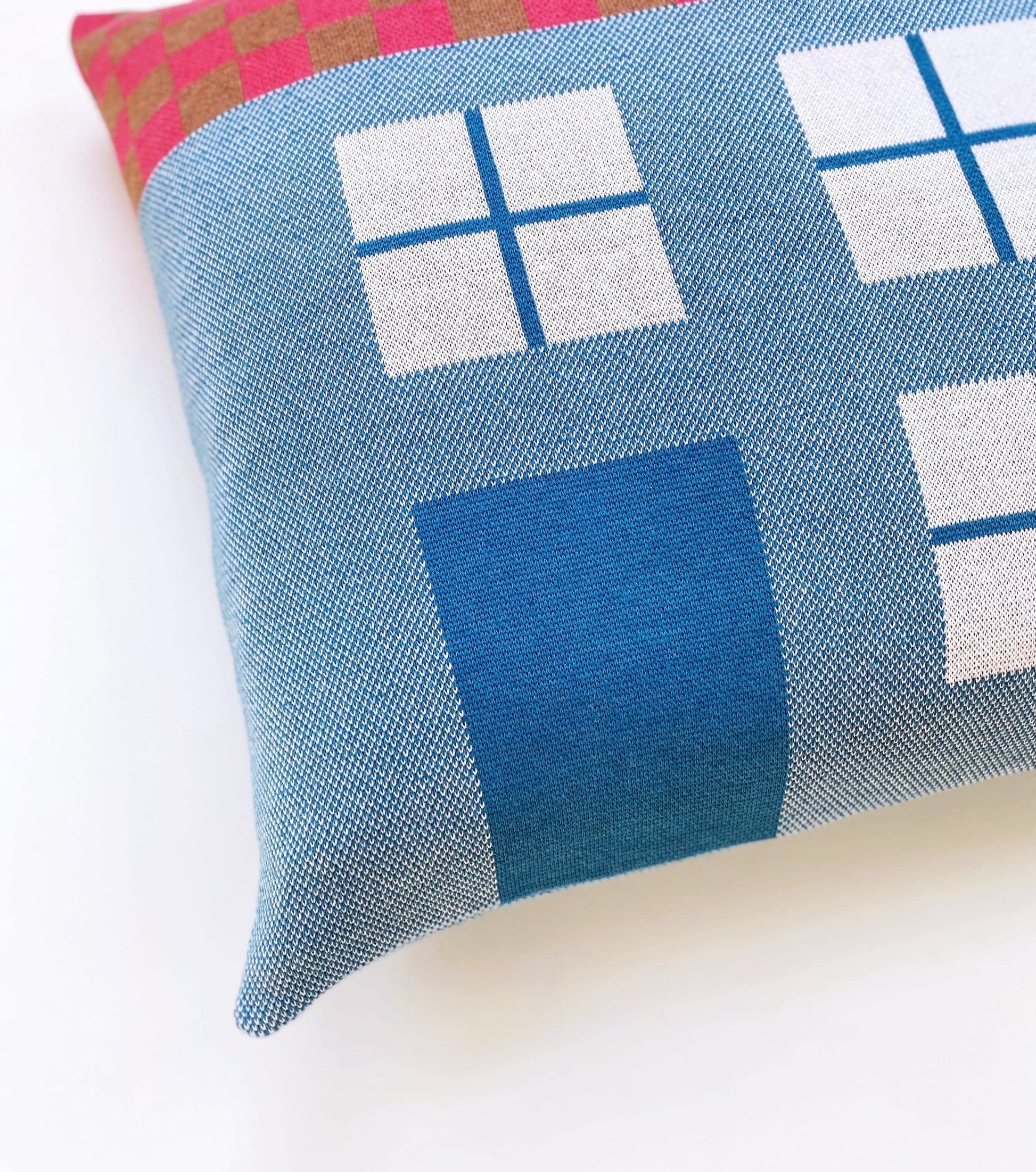 Decorative knitted house shaped pillow with geometric pattern on a white background