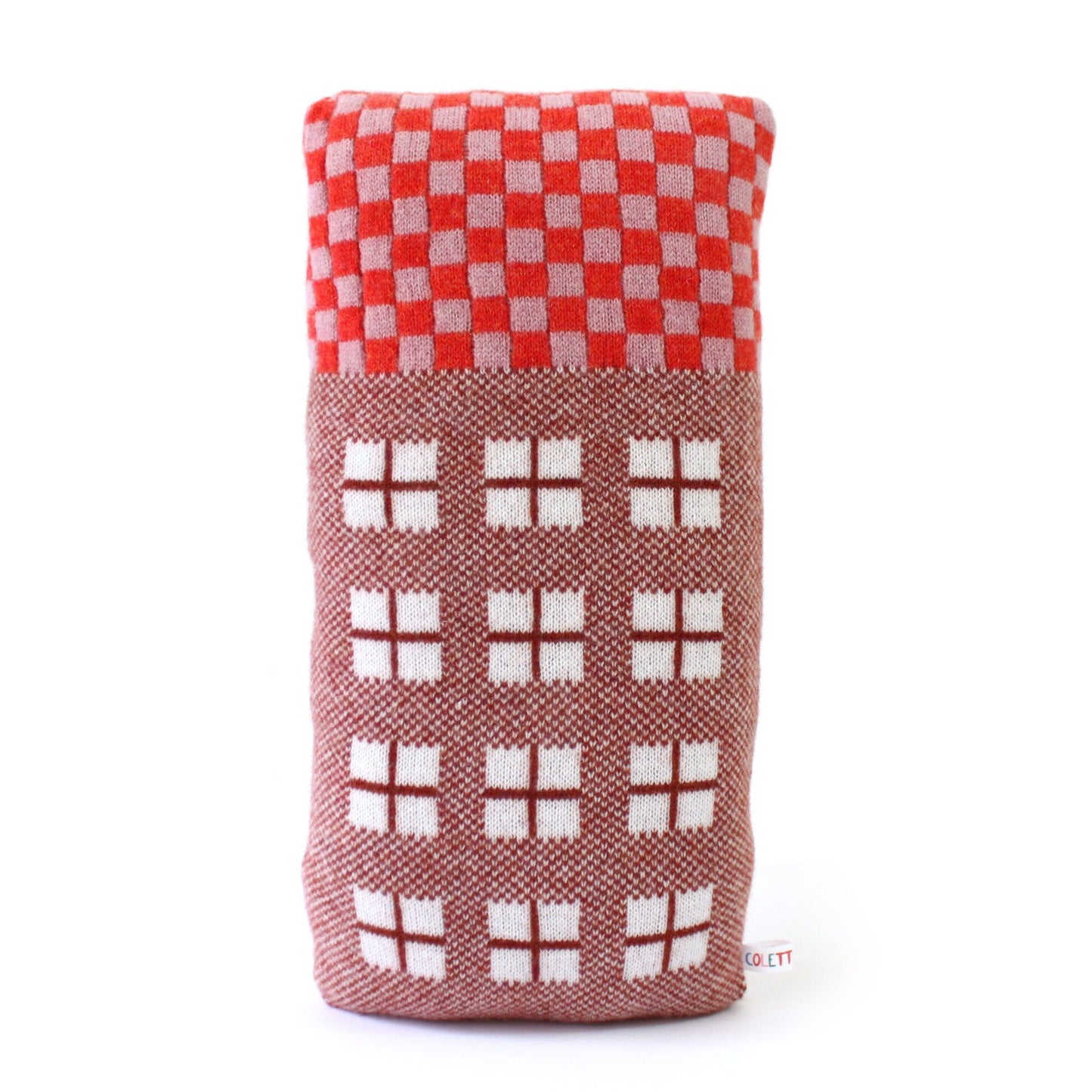 Colorful knitted house pillow with red and white checkered roof on a white background