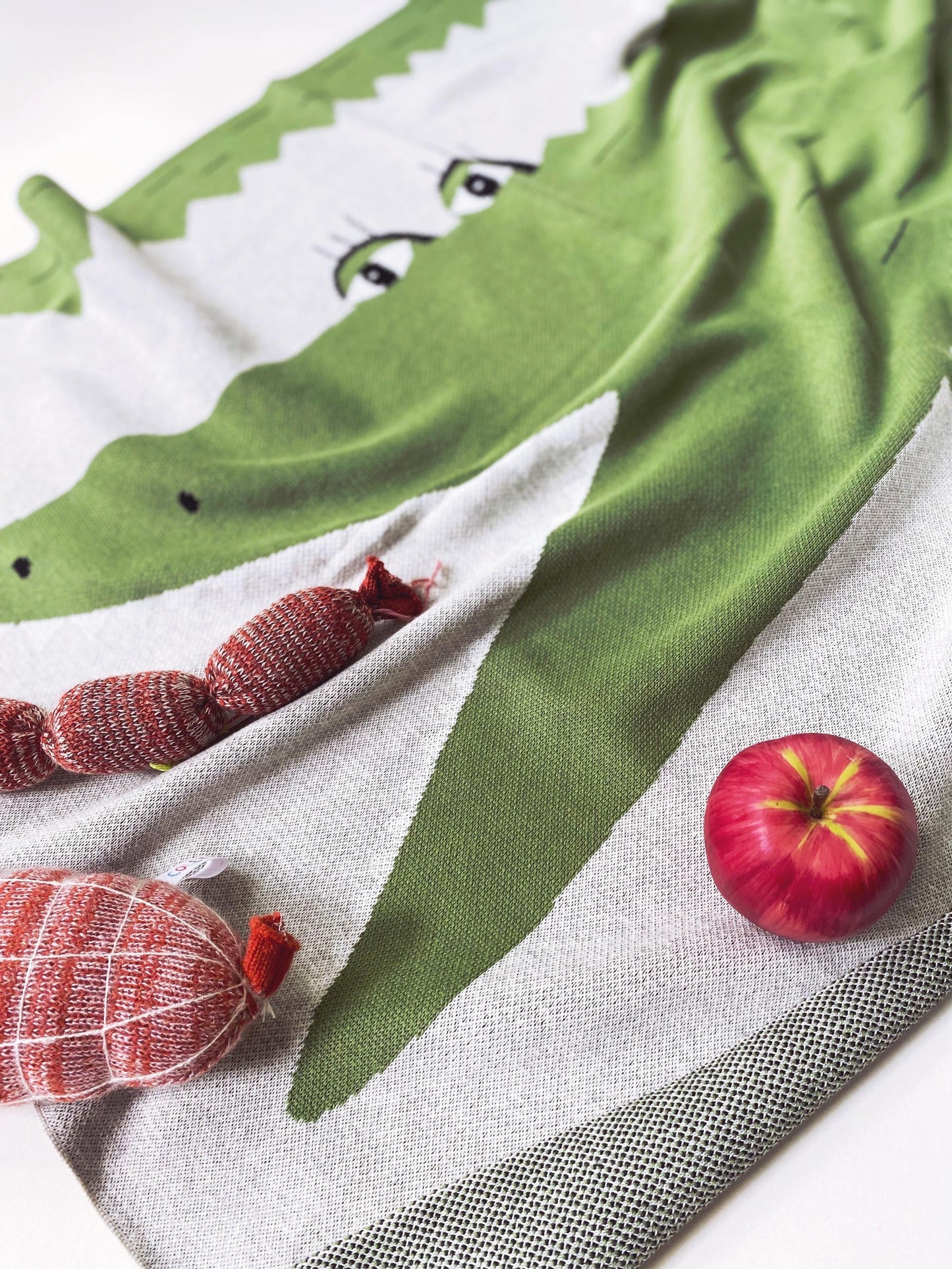 Detail of a knit baby blanket with green alligator character design