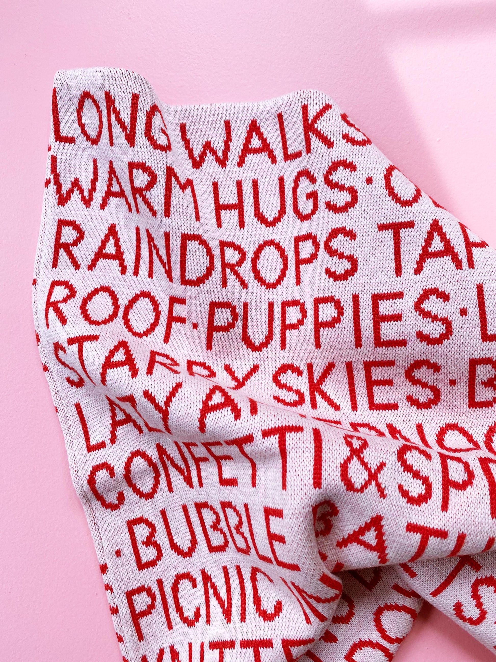 Knitted fabric pillow with red text on a pink background