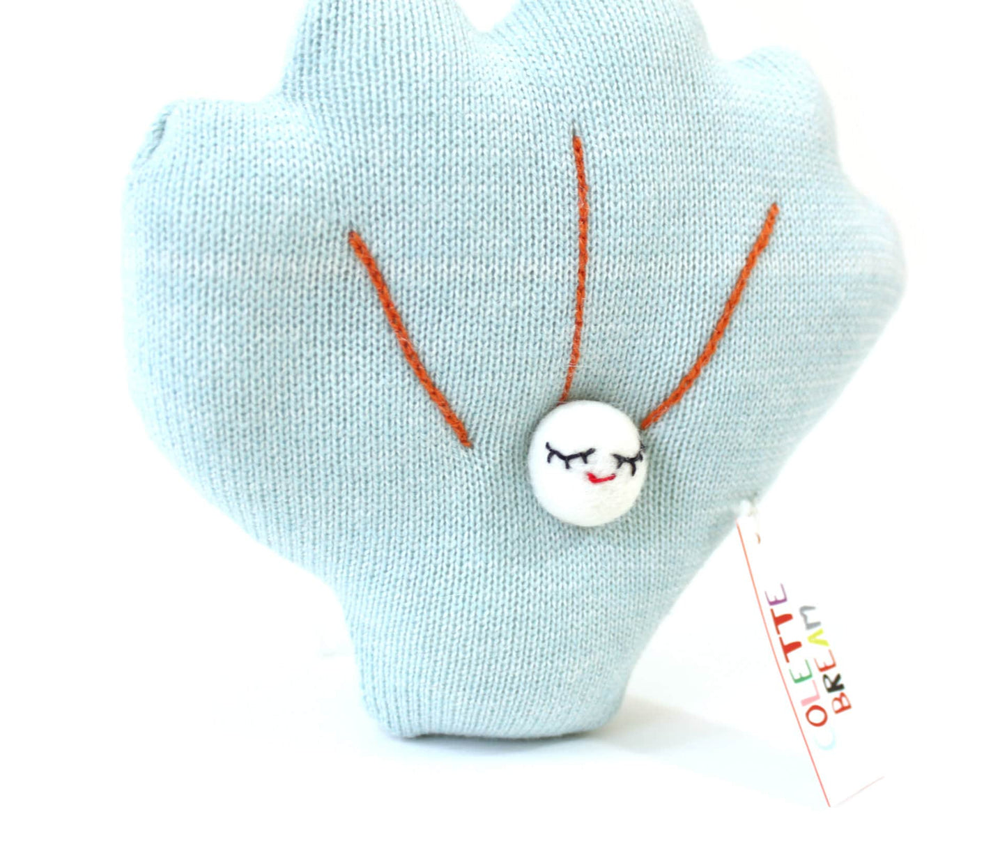 Light blue shell-shaped knitted plush toy with a smiling face and orange details on a white background
