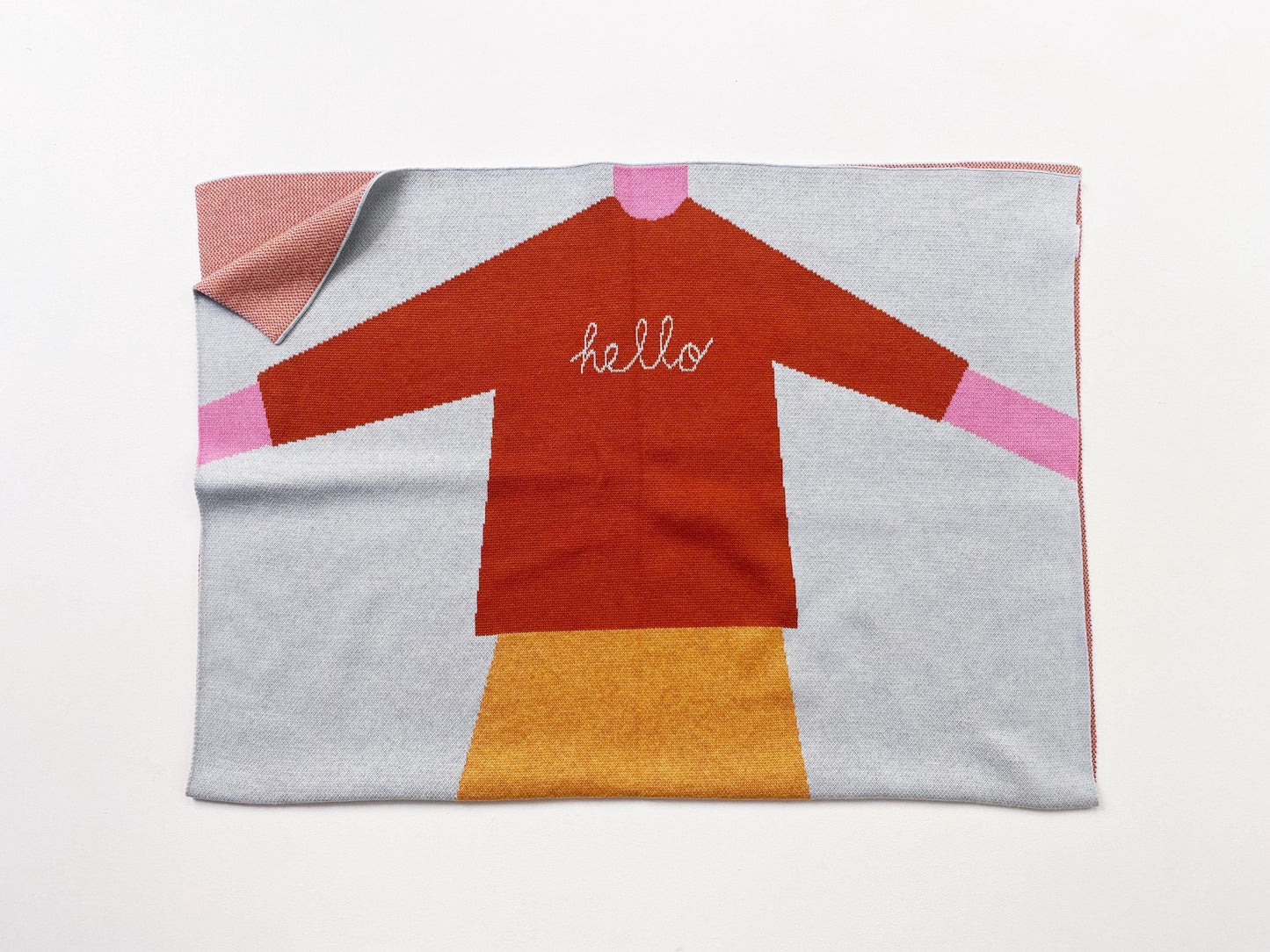 Knit blanket with a girl's dress design featuring the word 'hello' on a white background