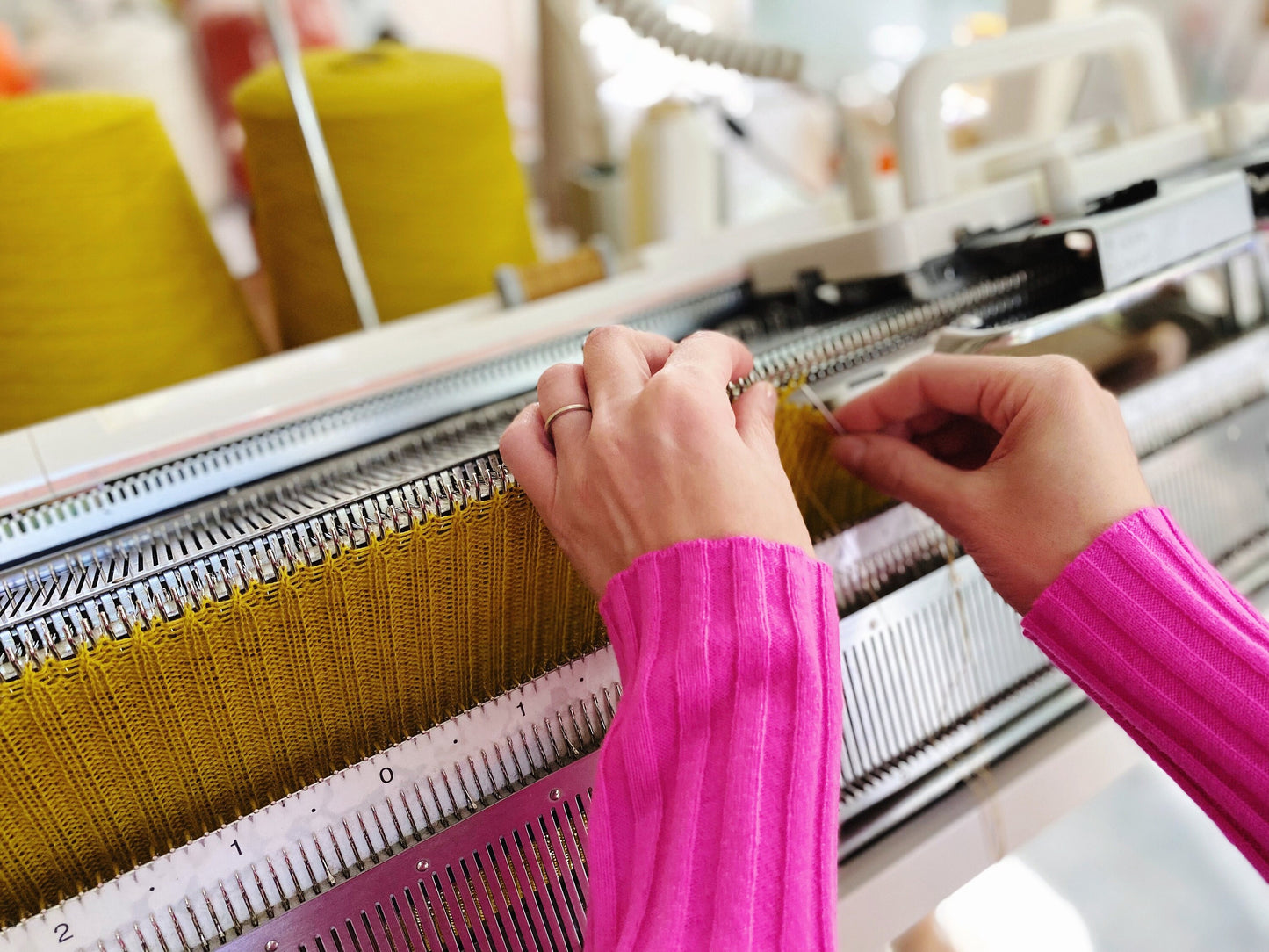 Person working with yarn on a knitting machine in a workshop setting