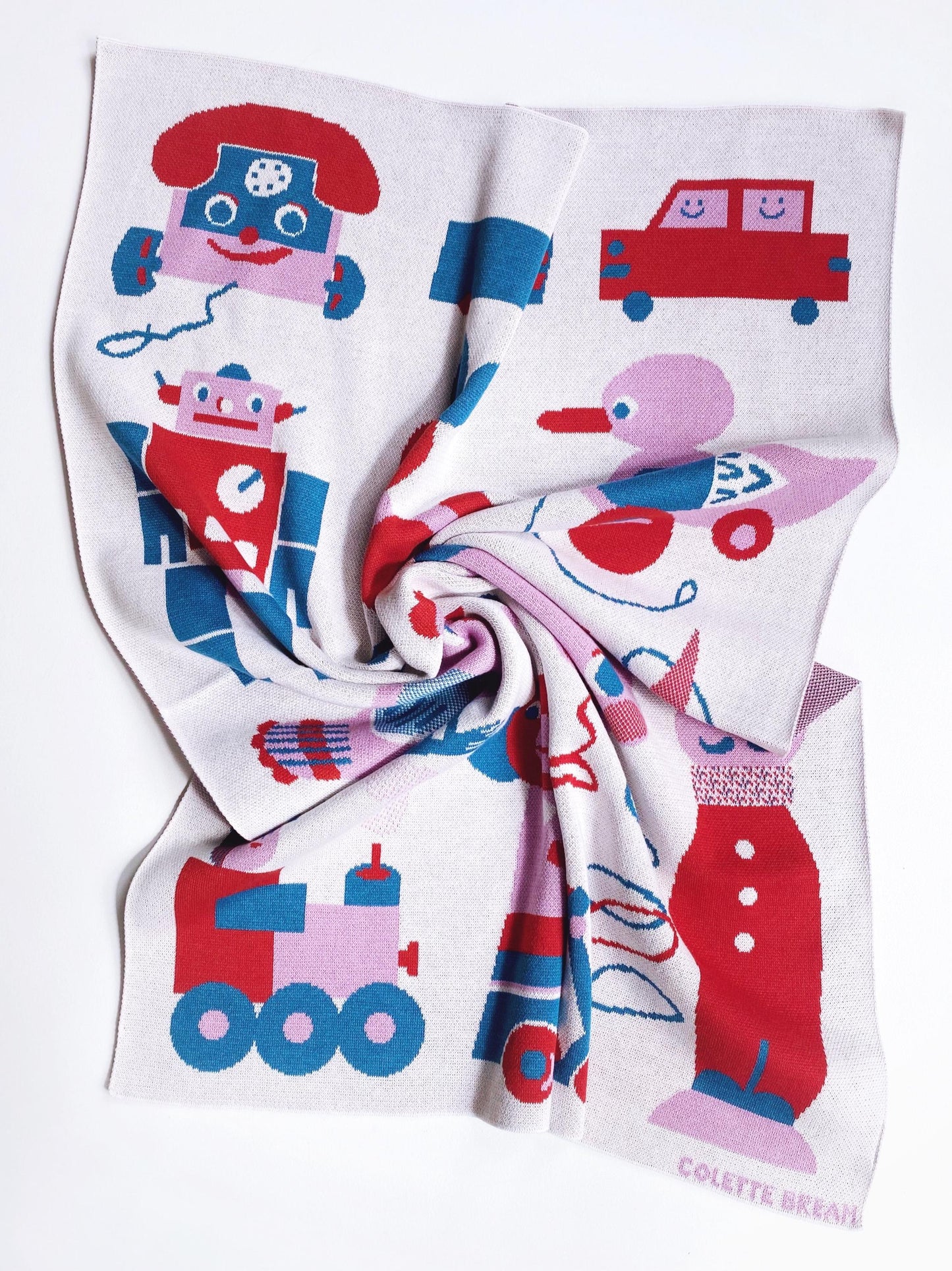 Children's knitted blanket with colorful vintage toy designs on a white background