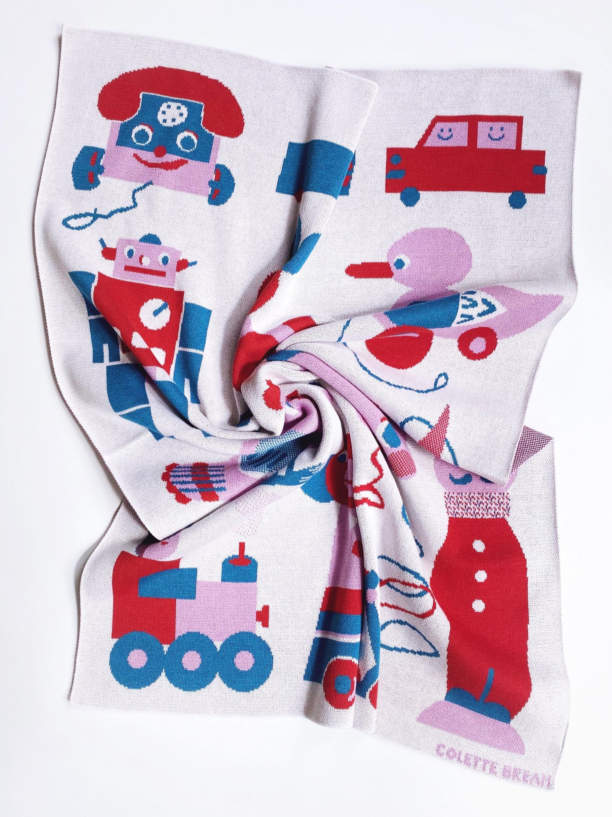 Children's knitted blanket with colorful vintage toy designs on a white background