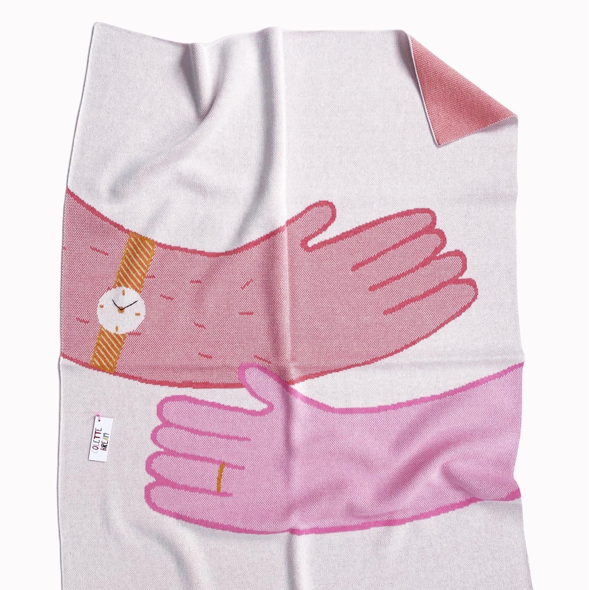 Knit baby blanket with pink hands in a hug embracing on a white background