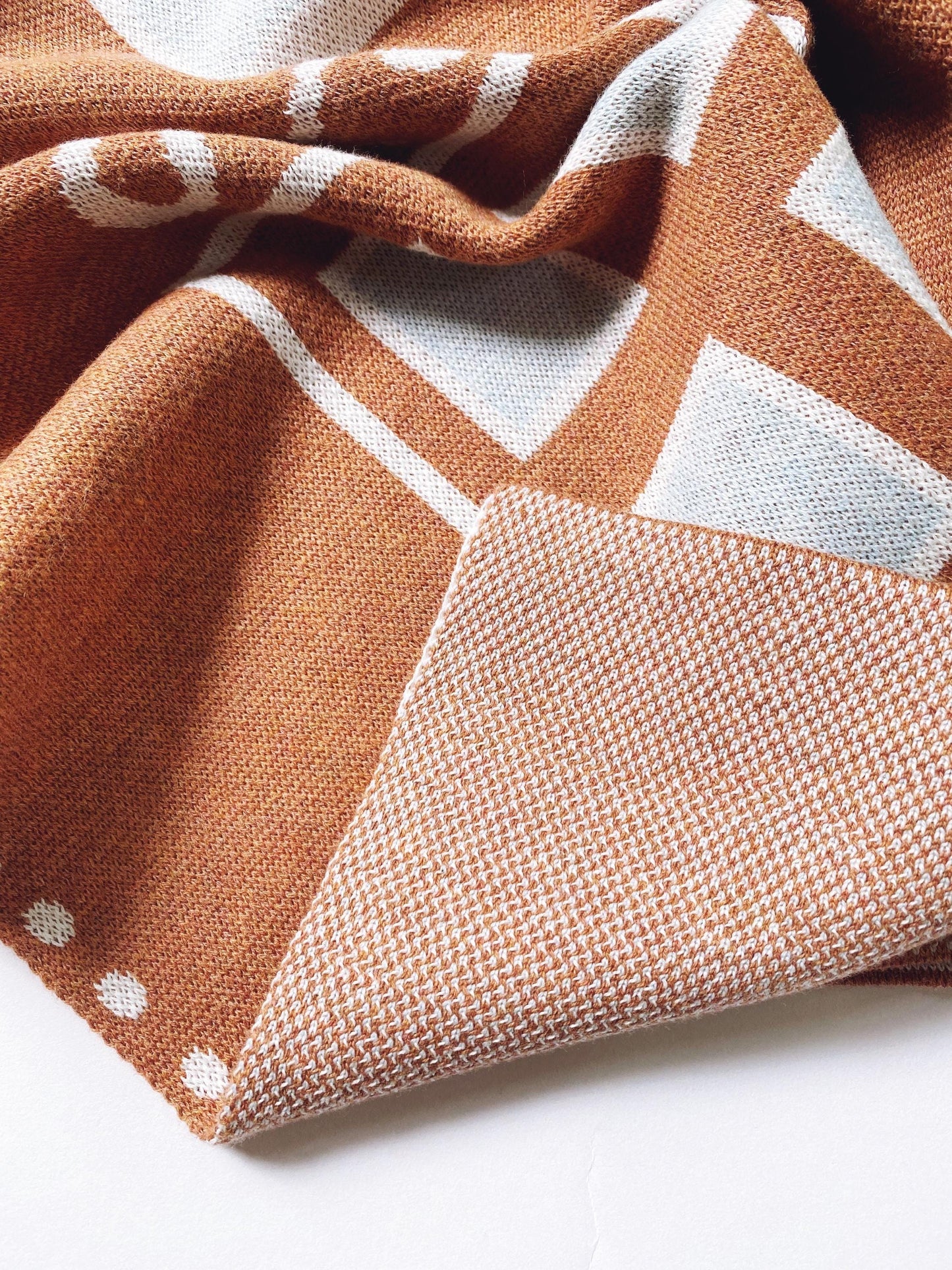 Close-up of a knitted fabric with brown geometric pattern on a white background
