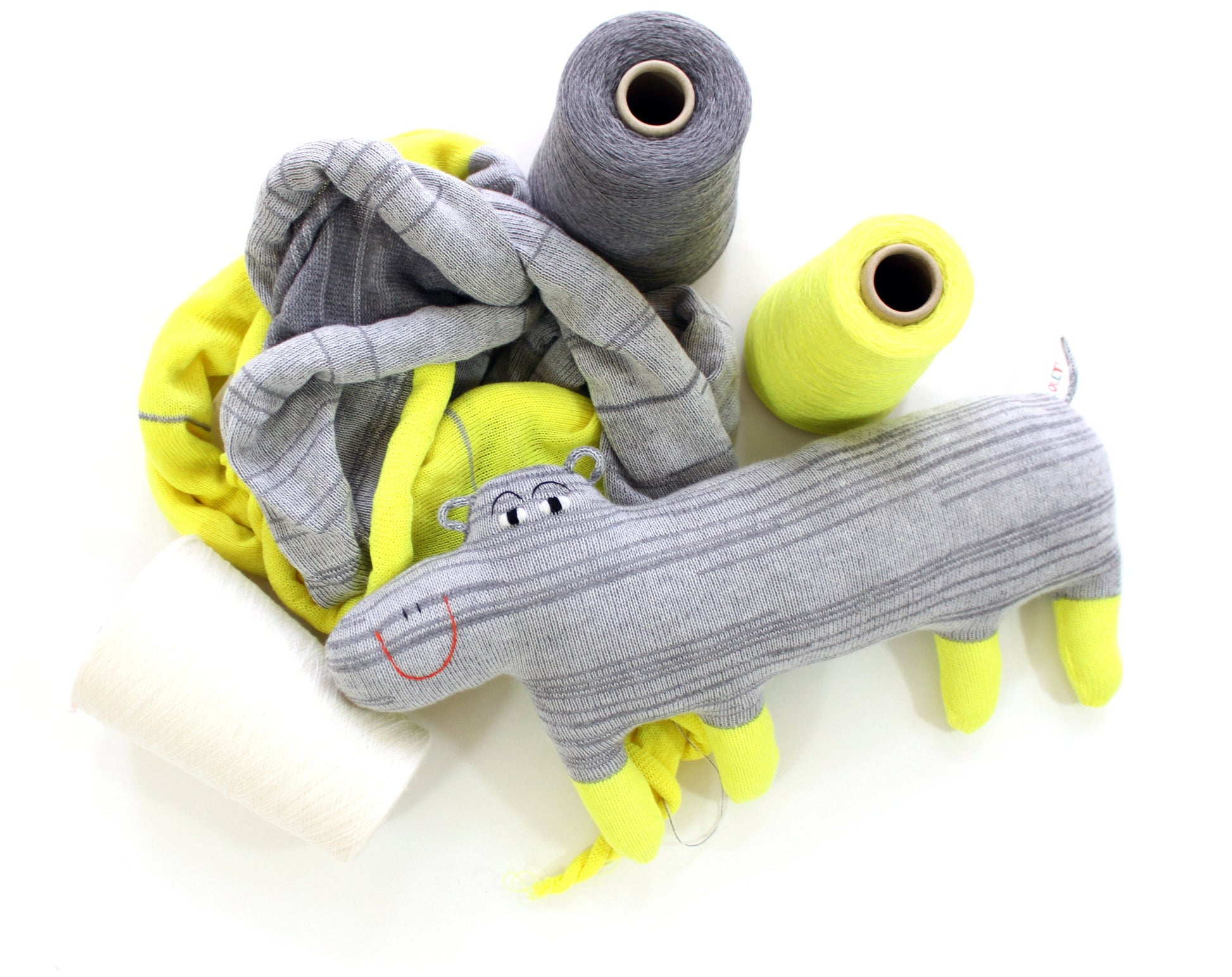 Gray and yellow fabric rolls with a hippo toy on a white background