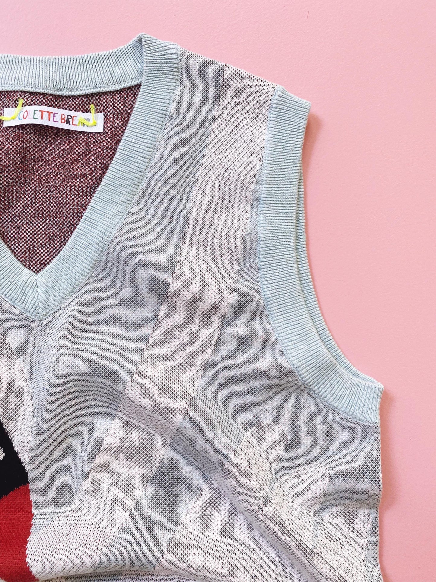 Light blue sweater vest on a pink background
