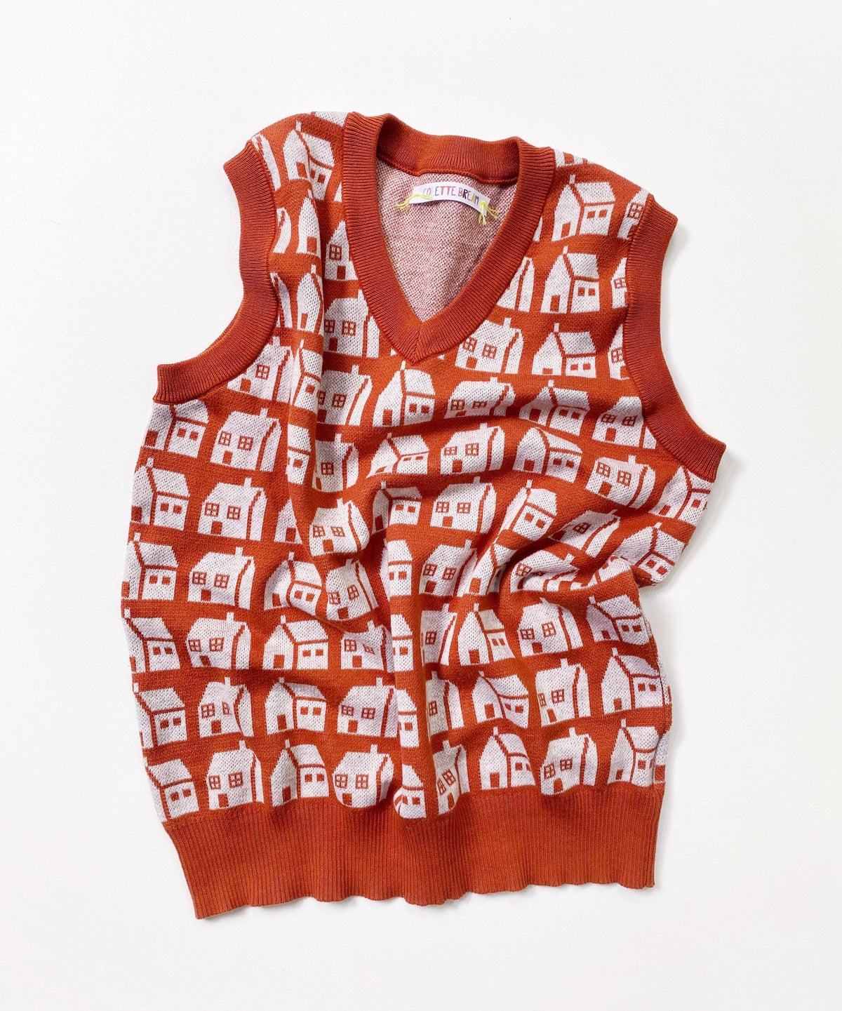 Orange sleeveless sweater vest with white house pattern on a white background