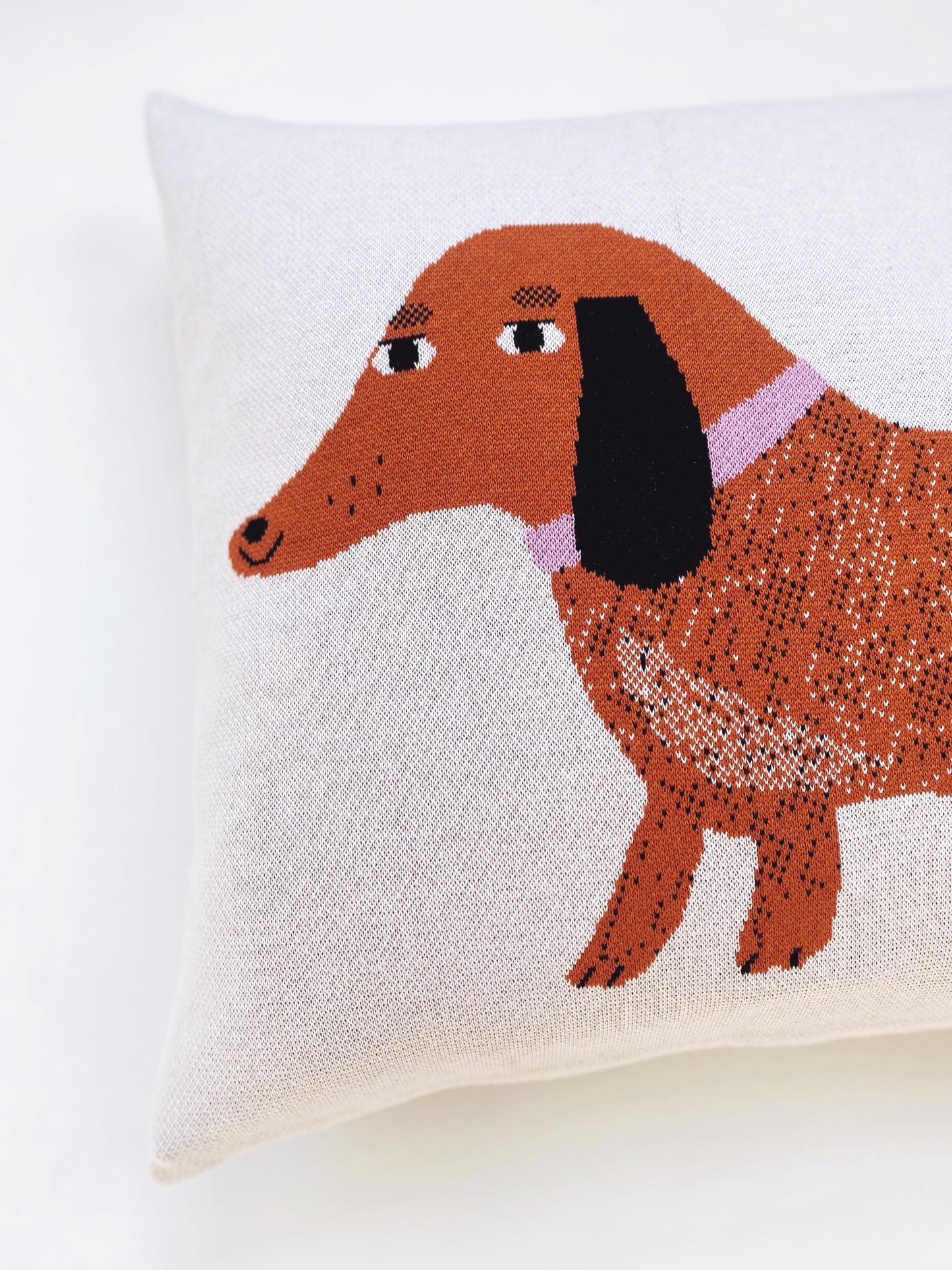 Decorative pillow with a dachshund design on a white background