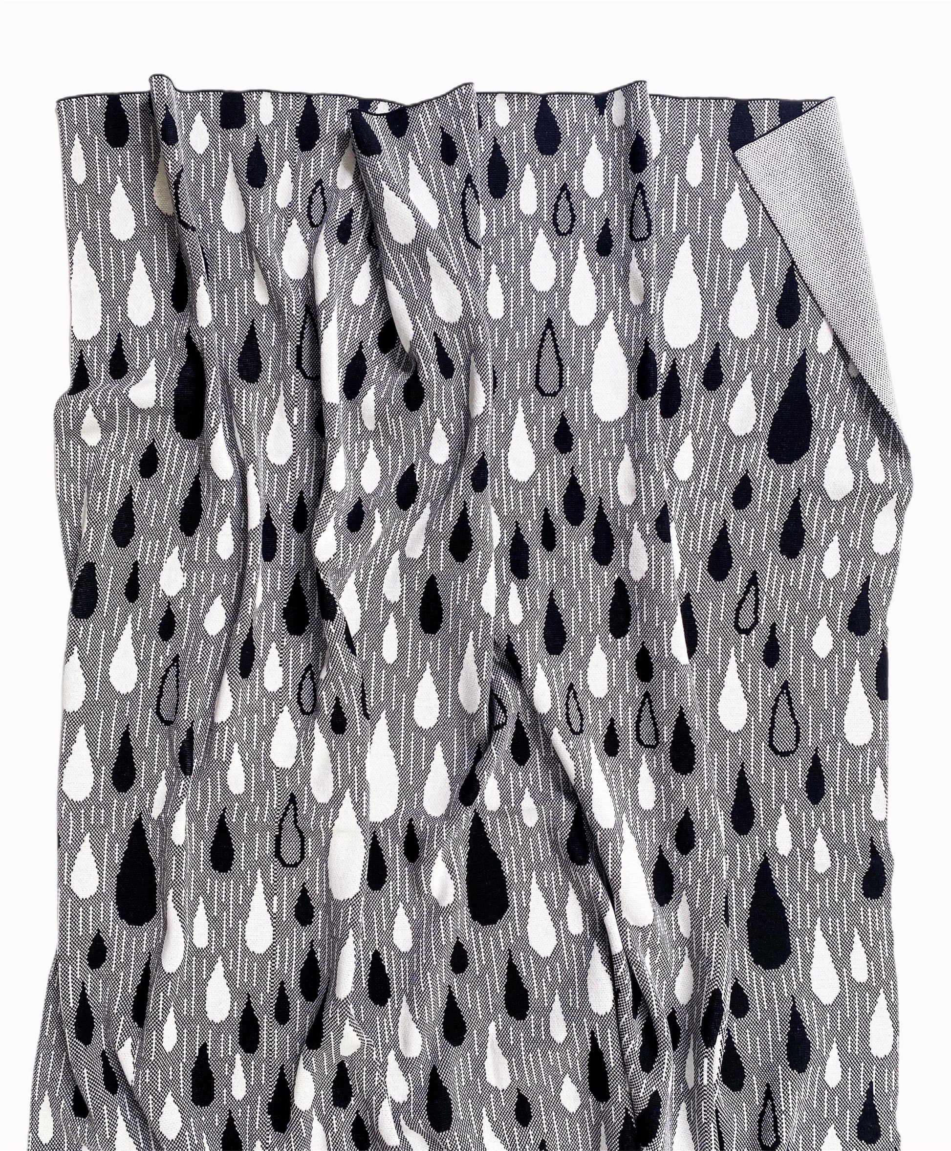 Knitted blanket throw with black and white raindrop pattern on a white background