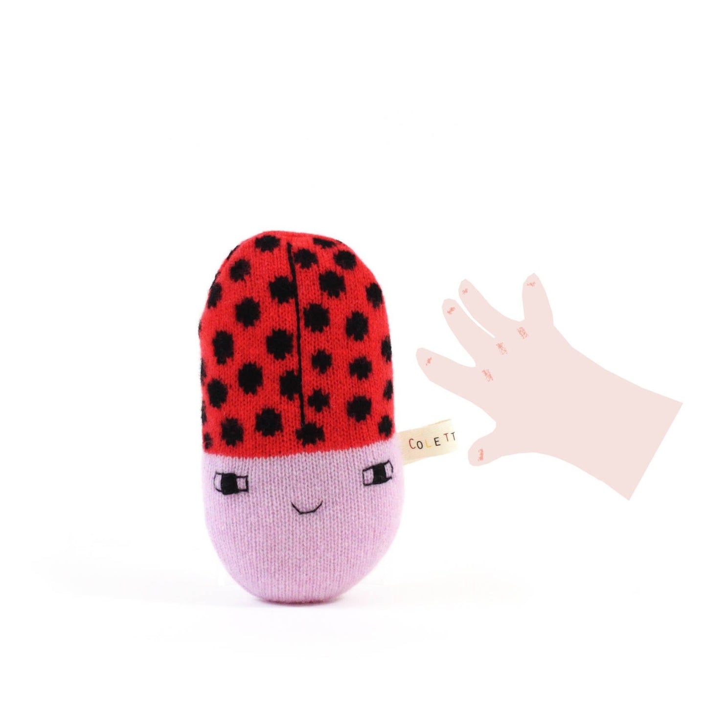 Small baby rattle plush toy shaped like a ladybug with red and black polka dot top and pink bottom on a white background