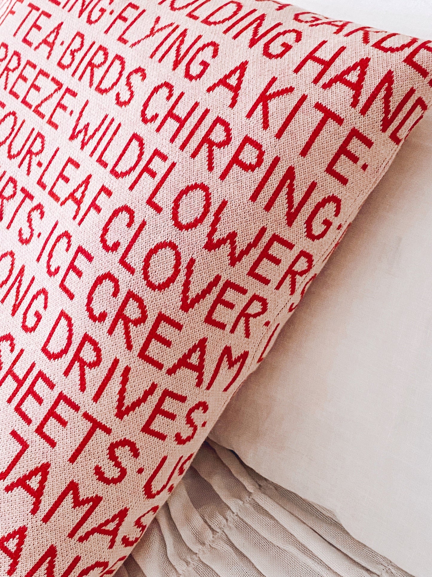 Knit fabric pillow with red text on a pink background