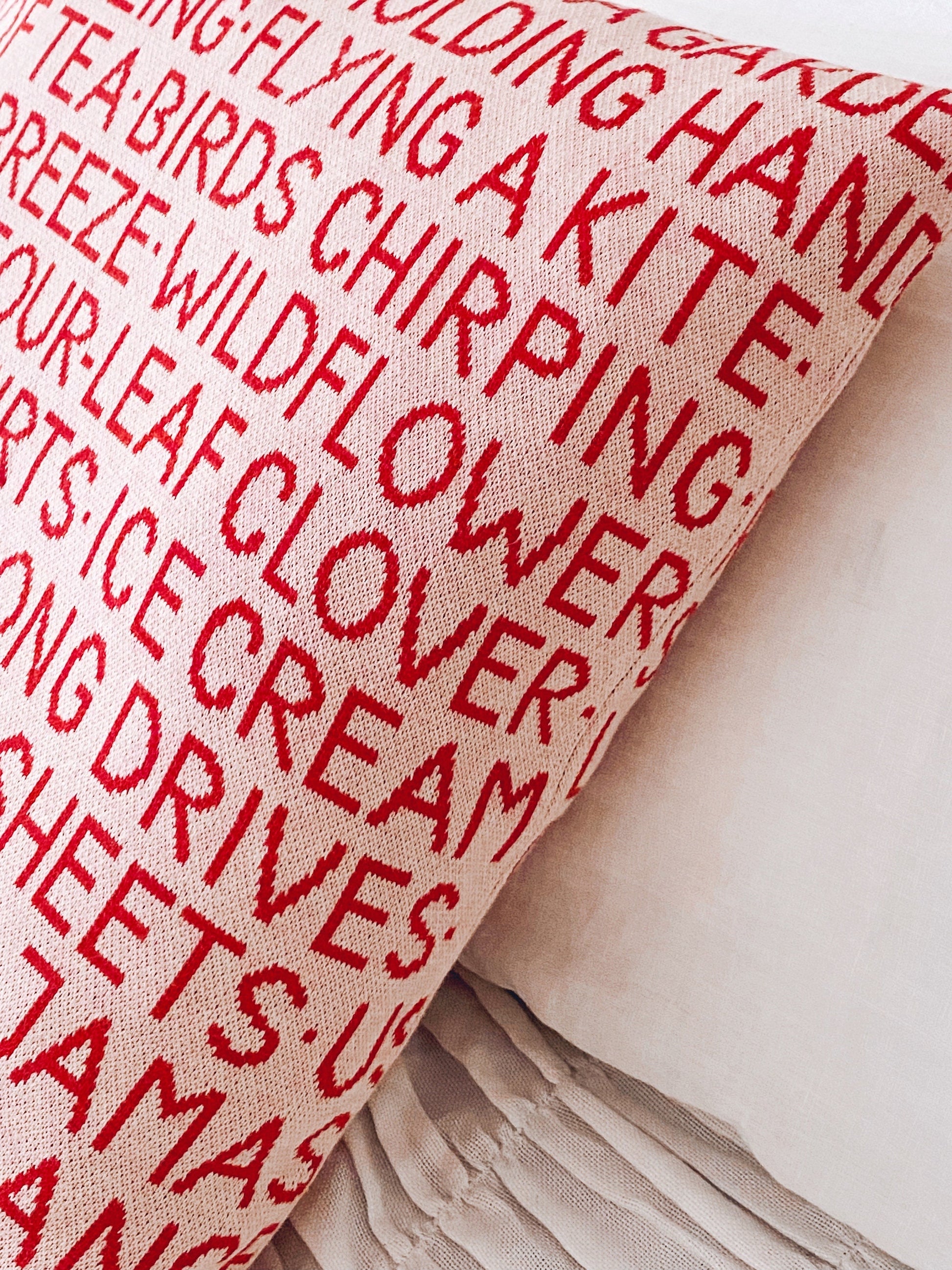 Knit fabric pillow with red text on a pink background