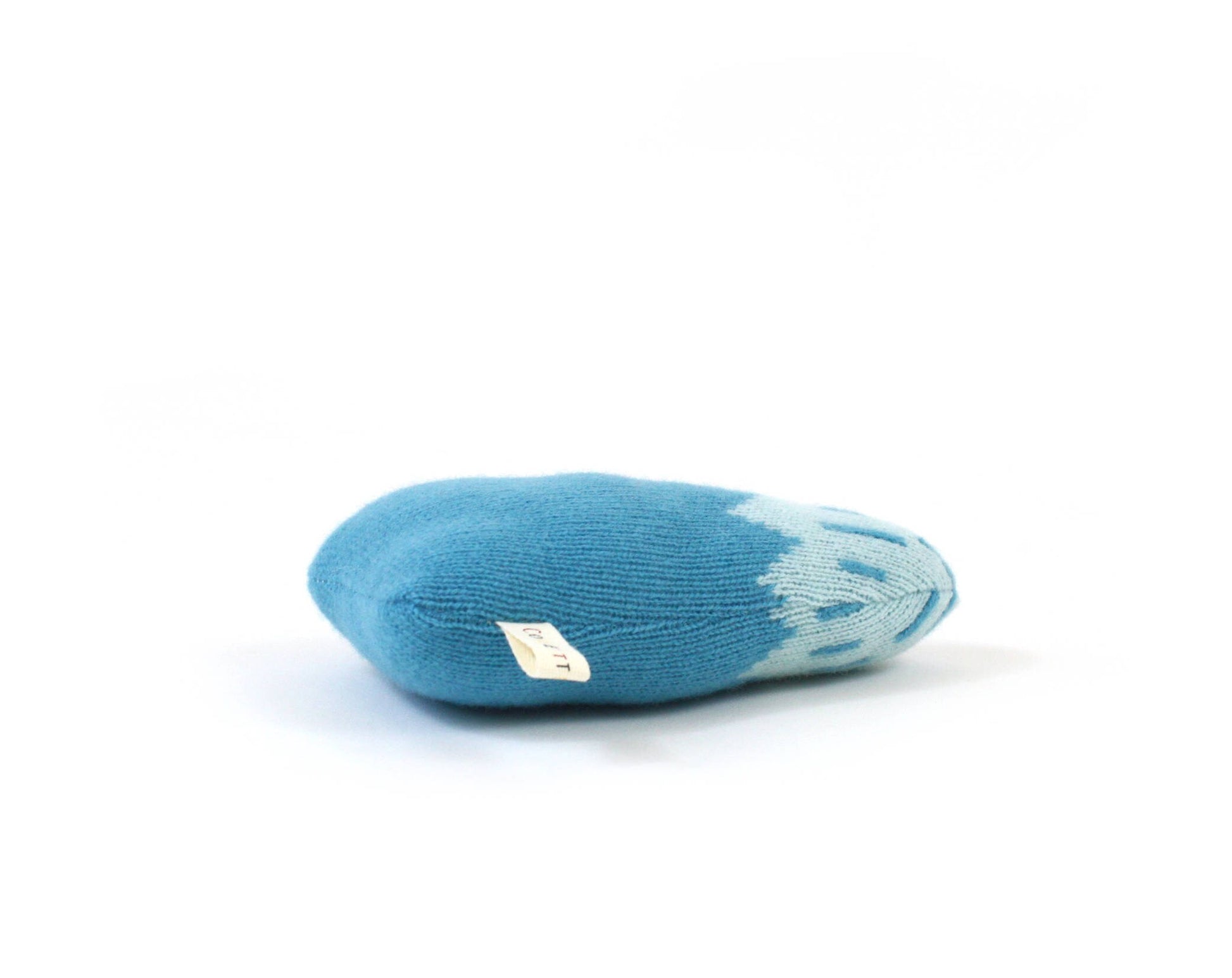 Blue knitted baby rattle plush toy shaped like a mountain with white accents on a white background