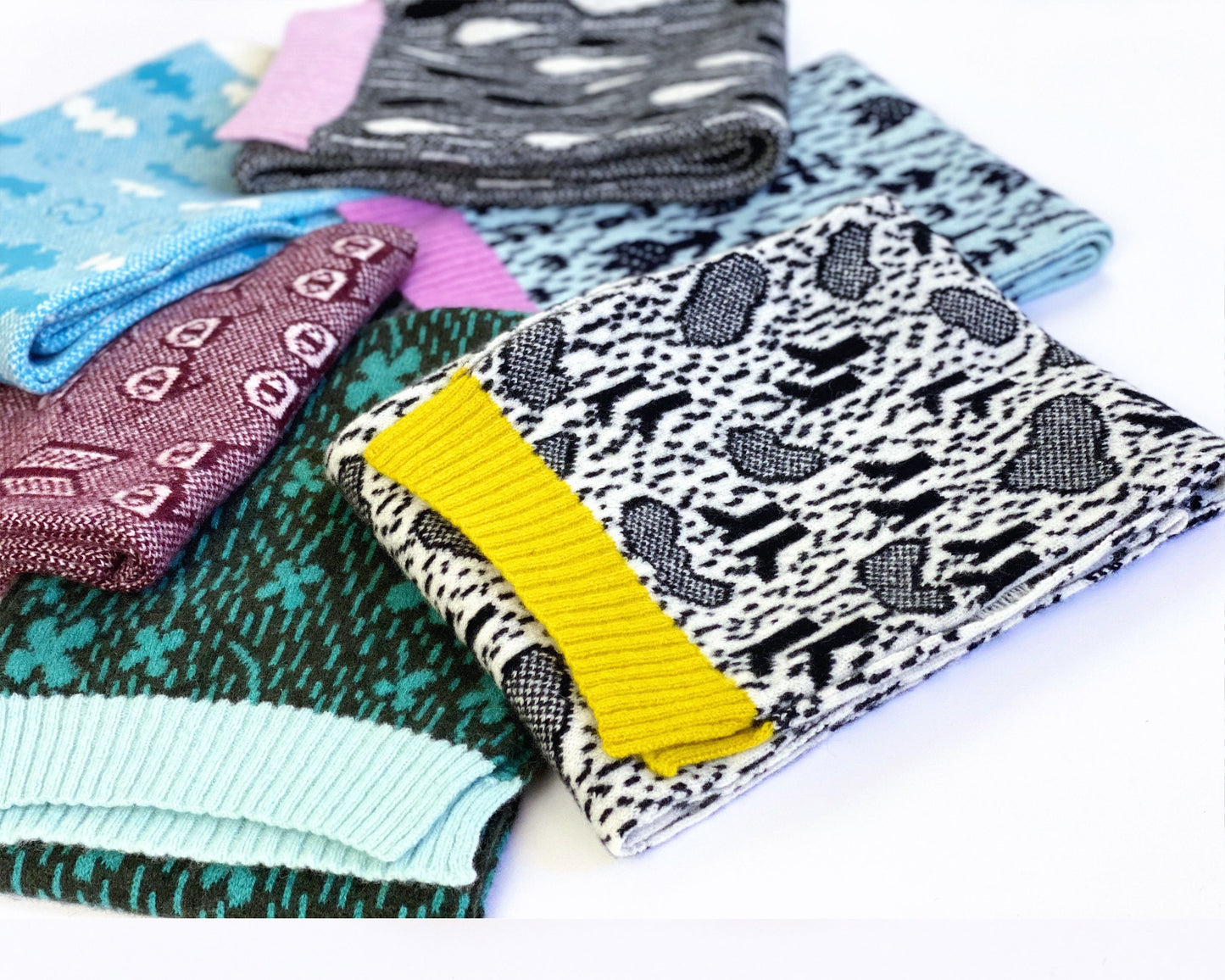 Collection of patterned knitted lambswool scarves on a white background