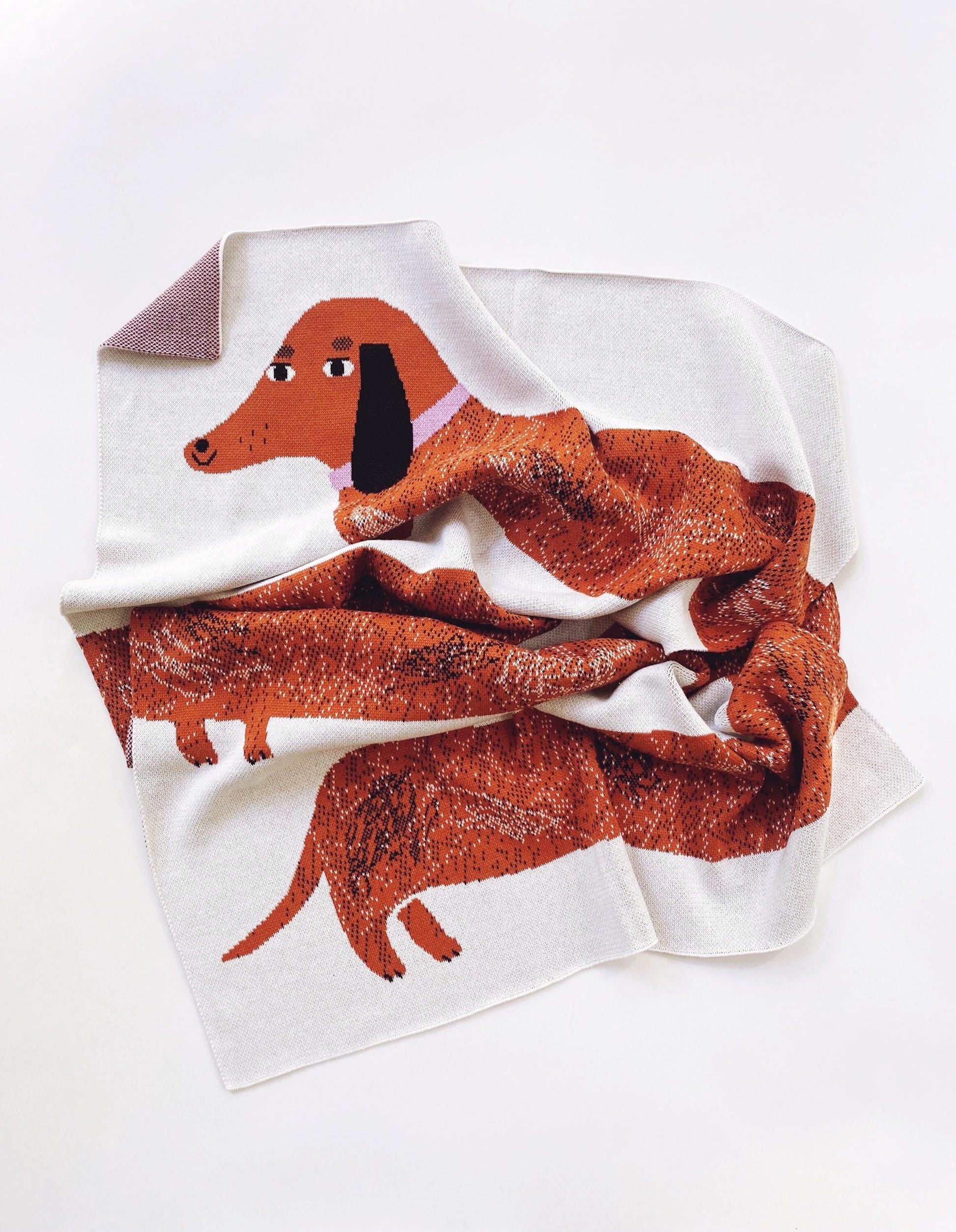 Knitted blanket with a dachshund design on a white background