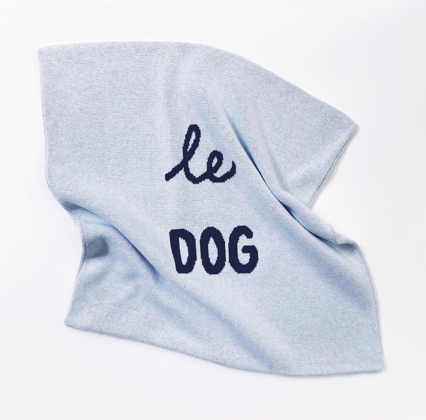 Light blue knitted pillow with 'le dog' text on a white background