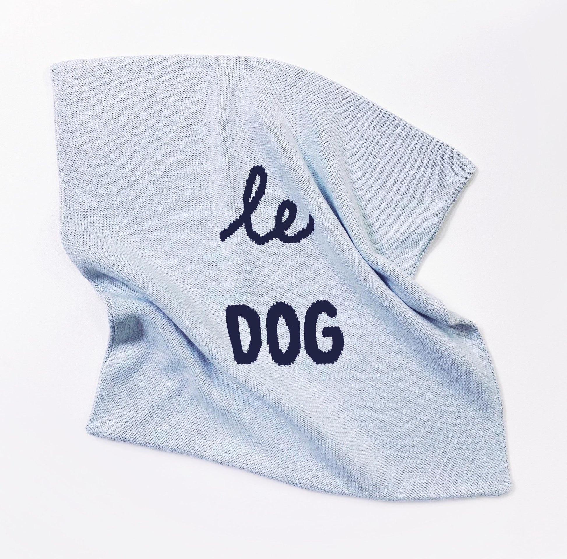 Light blue knitted pillow with 'le dog' text on a white background